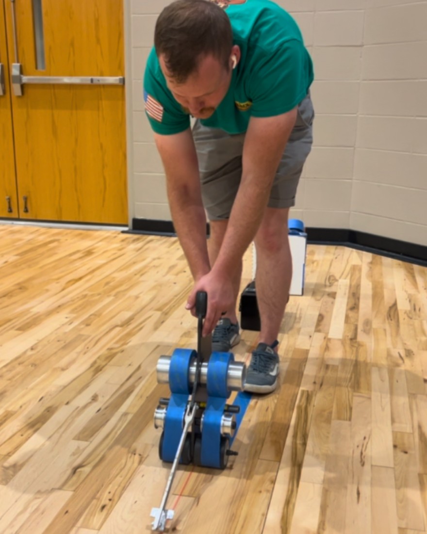 Applying the tape for basketball court lines to be painted during the refinishing process.