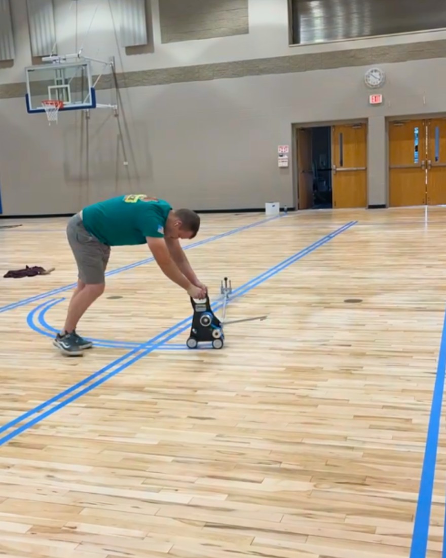 Applying the tape for the basketball jump circle. After this tape is applied, the lines will be painted.